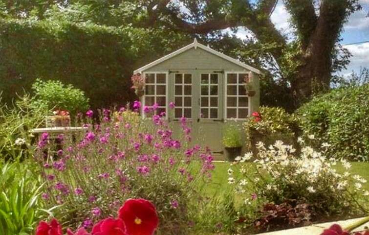 TIger Sheds Corner Summerhouse in garden with plants and flowers