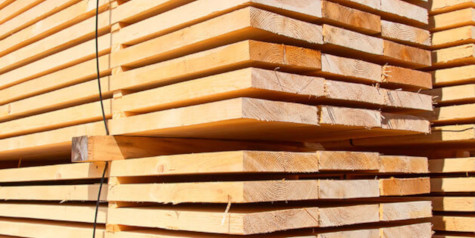 A picture containing pile of log cabin pine planks