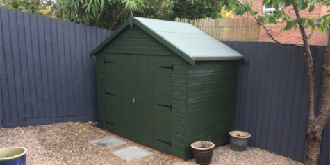 A picture containing a painted green garden shed