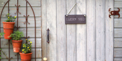 A picture containing a wooden shed door with hanging sign