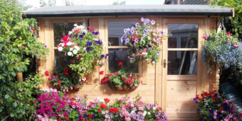 A picture containing a log cabin with hanging baskets of flowers