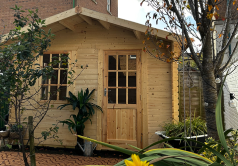 A picture containing a Tiger Sheds wooden log cabin with georgian style windows and doors