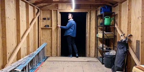 A picture containing a man in a shed switching on the electric lights
