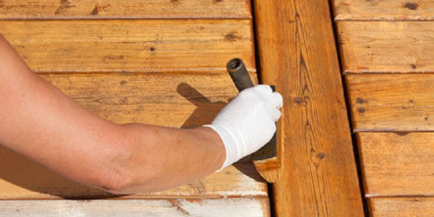 A picture of a man applying shed preserver to the wooden shed