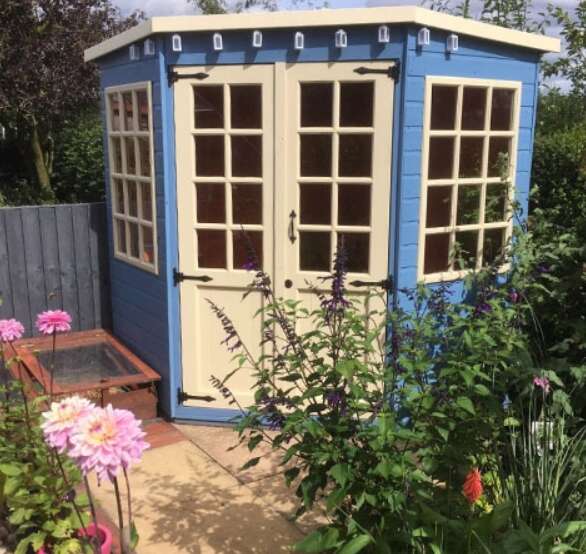 Tiger Corner Summerhouse painted in blue and cream in garden with flowers