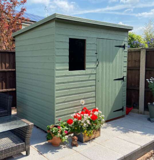 Tiger Shiplap Pent Shed painted green with flower boxes and plants on patio