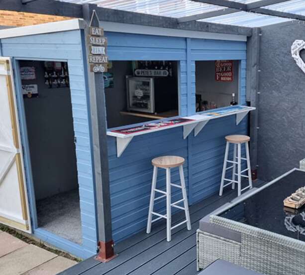 A TigerFlex Pent Shed painted in Blue, converted to garden bar with bar stools and garden deck