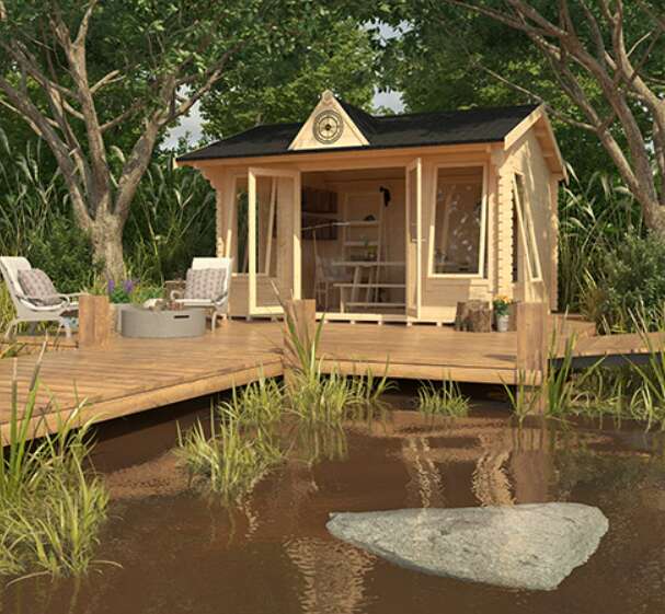 Tiger Copley log cabin with clock, in garden with trees, pond, decking and garden furniture