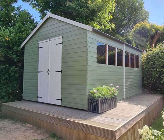 Tiger heavyweight workshop shed, painted green and white, garden, trees, bushes, potted plants, garden deck