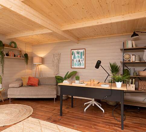 Tiger Sheds Optima Log Cabin inside with desk, table, lamp, sofa and shelves