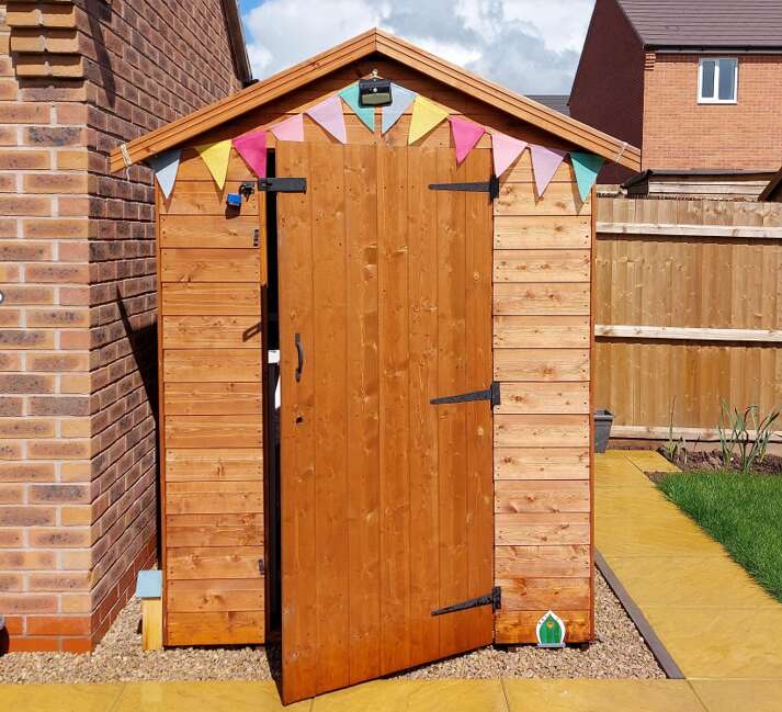 A picture containing a Tiger Shiplap Apex Shed with bunting in garden