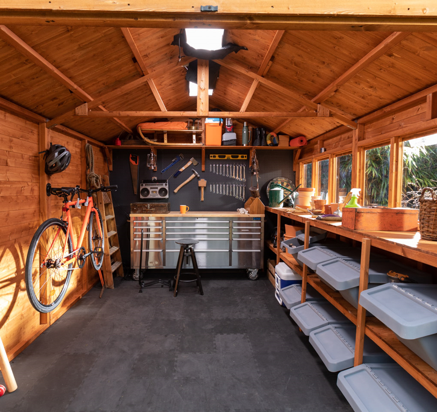 A shed with a bike, storage shelves, workshop, tools