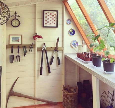 A picture containing the inside of a potting shed, tools hanging from walls