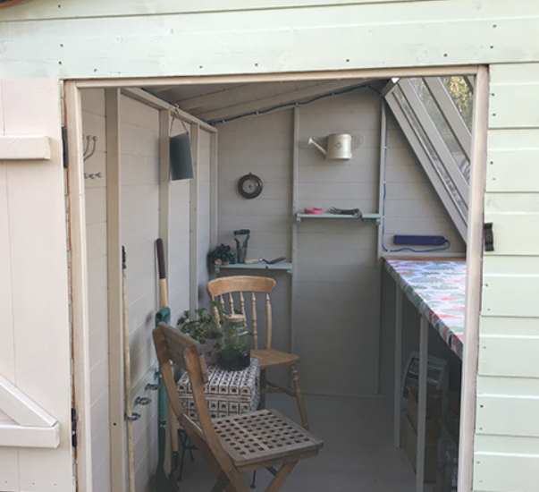 a potting shed with two chairs and a table