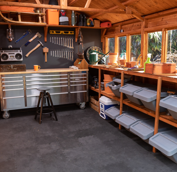 A picture containing a tool shed with work bench and shelves