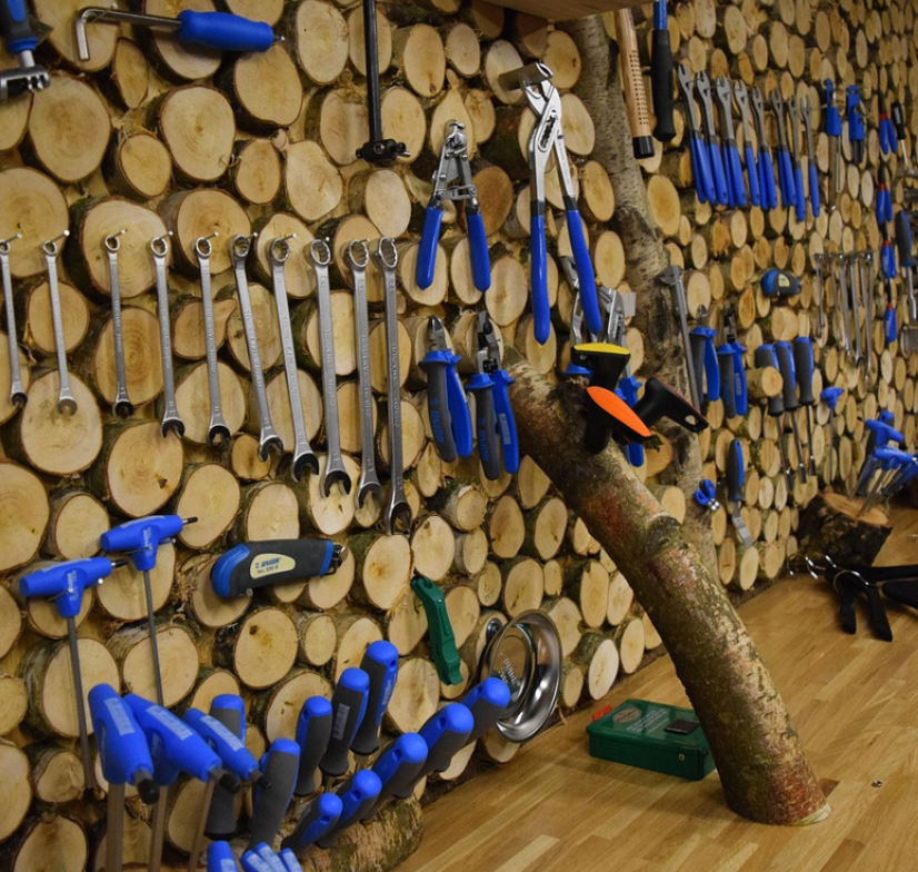 A picture containing a wall with wooden logs, hanging tools