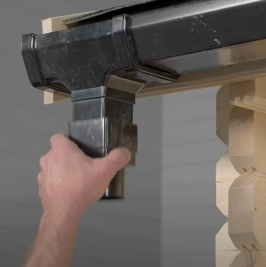 A picture of man fitting a connector to a shed gutter