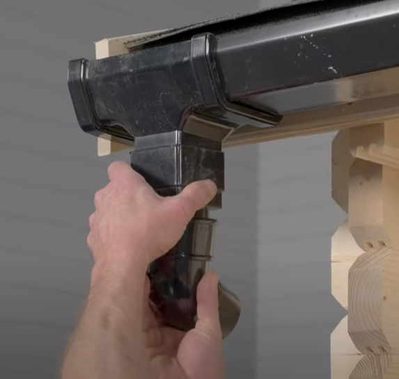 A picture of a man fitting a bend to a shed gutter connector