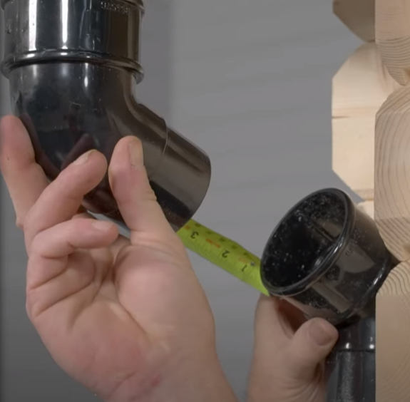 A picture of a man measuring a shed gutter