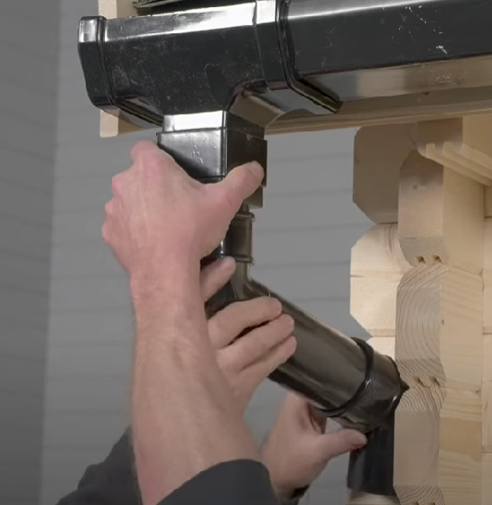 A man installing a shed downpipe