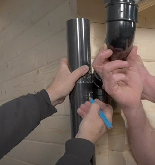 A man measuring a shed downpipe