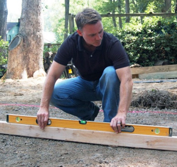 A person using a spirit level to build a shed base