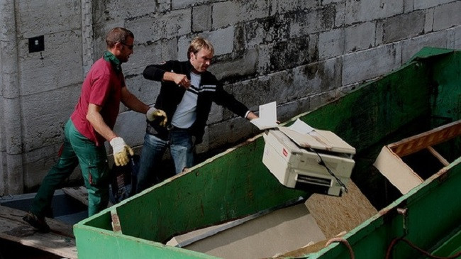 Two men throwing away junk from a shed